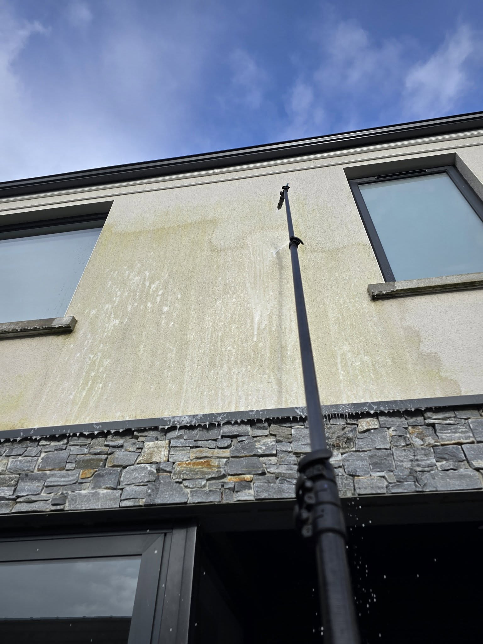 Professional softwashing of a modern building exterior in Northern Ireland